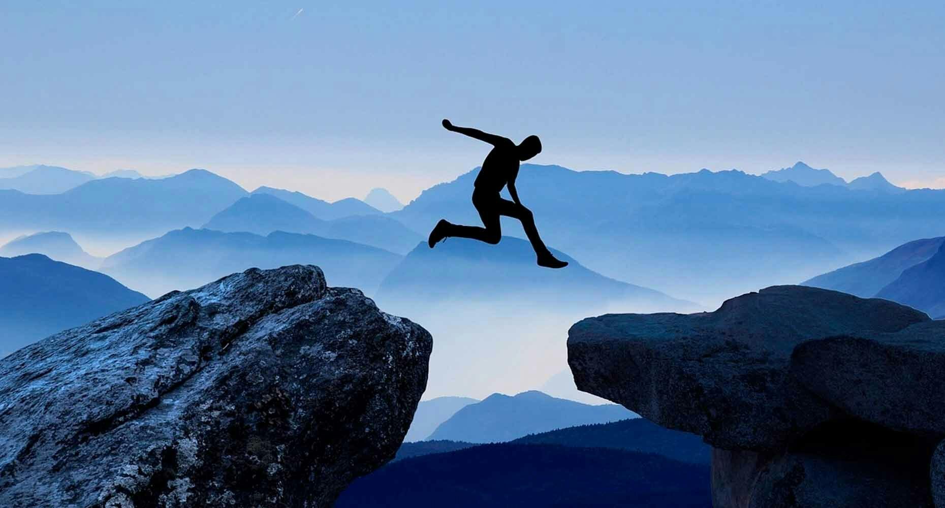 Person jumping across two rocks