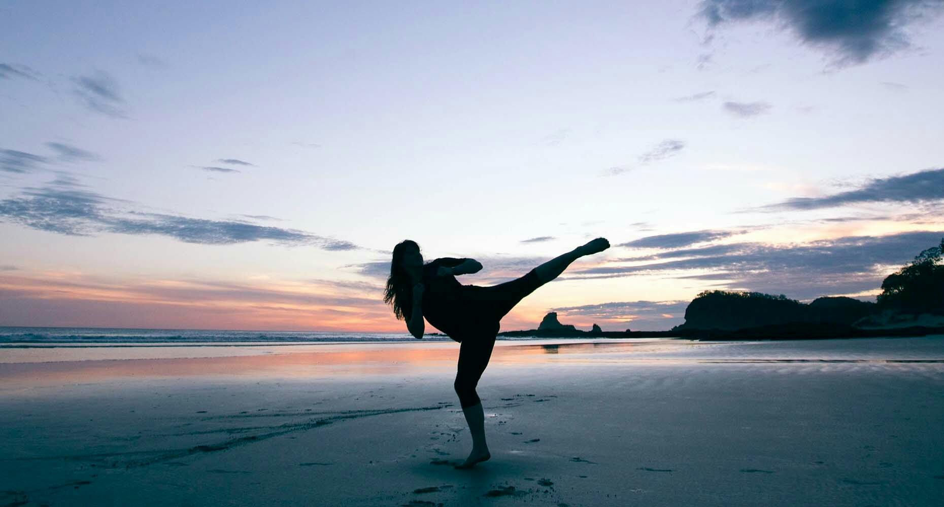 woman on beach at sunrise doing yoga