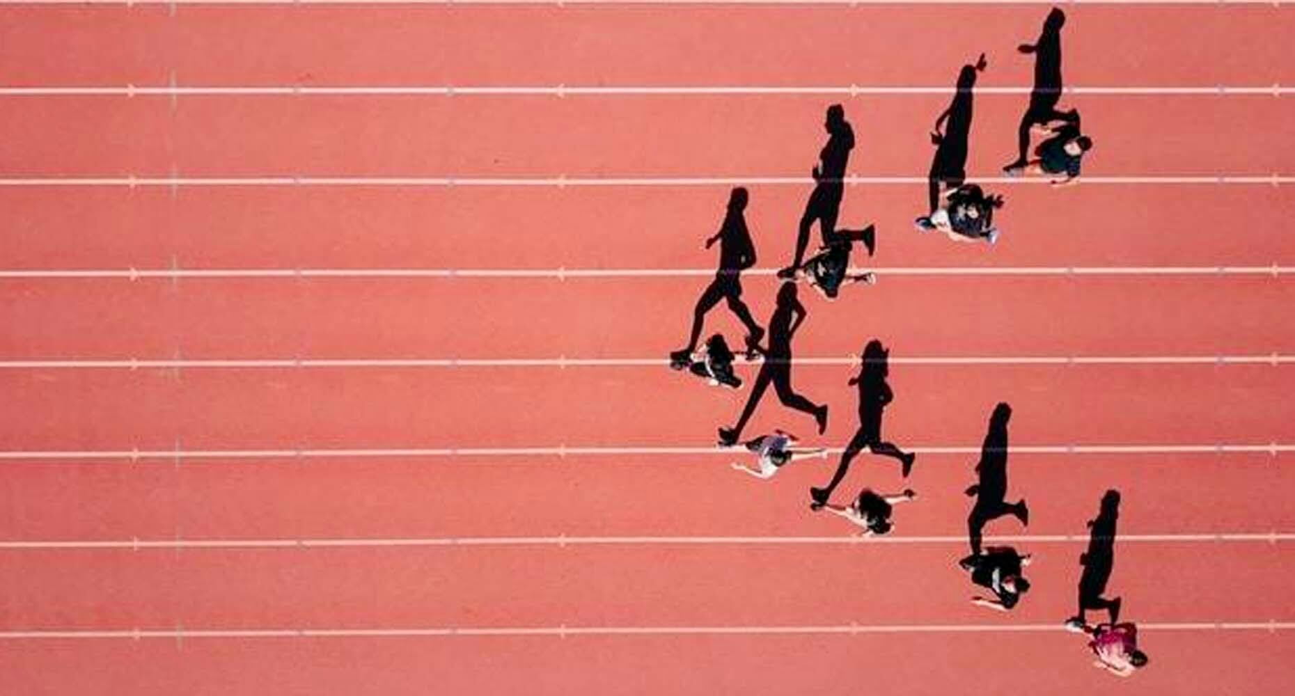 Silhouettes of runners casting shadows on a track