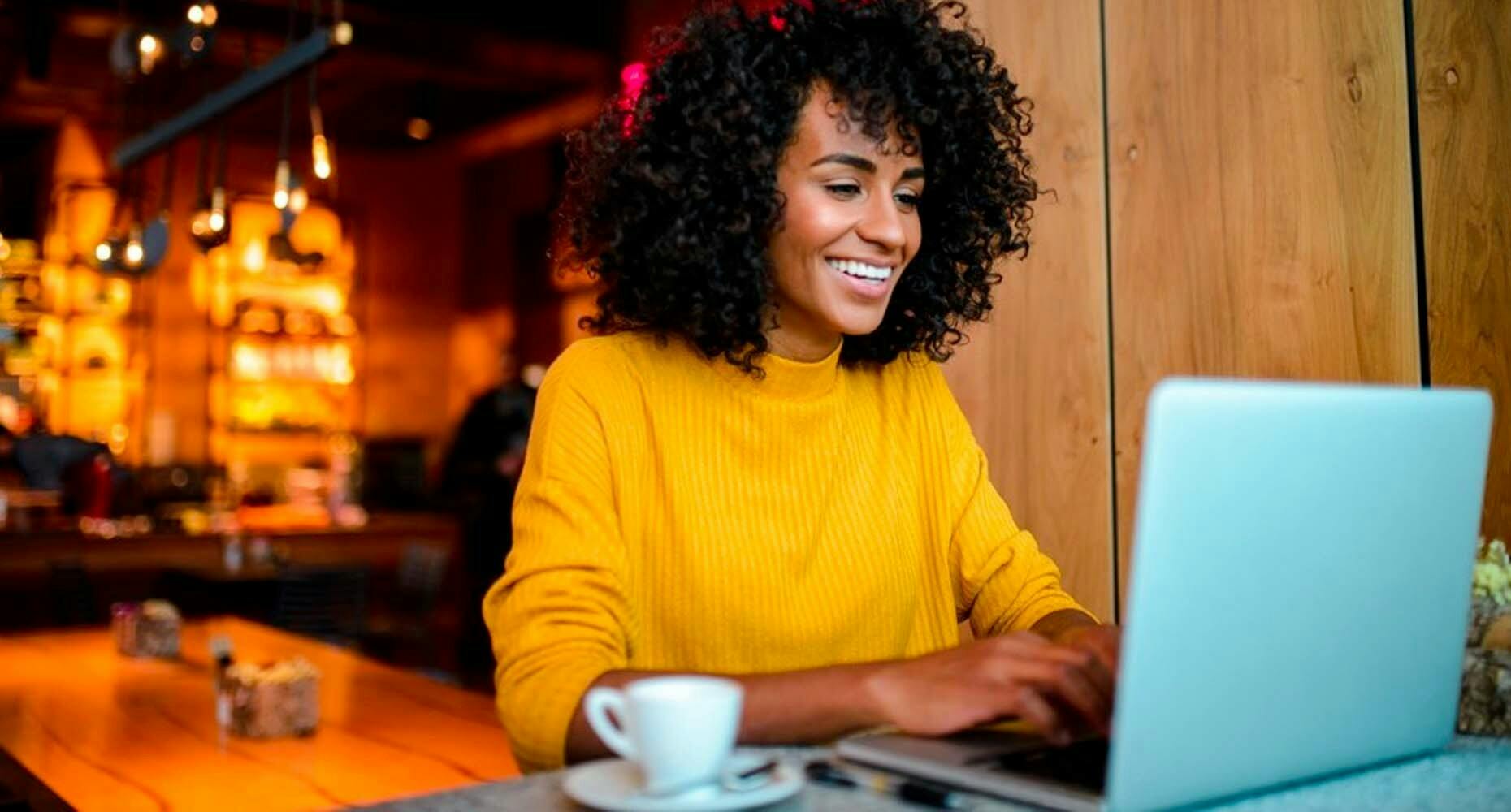 Smiling woman on a laptop in a bar