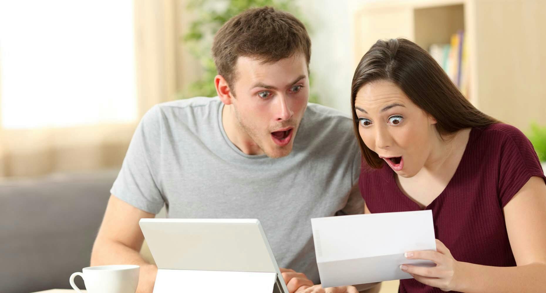 surprised man and woman looking at paper and tablet
